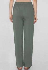 Pantaloni larghi con vita elastica in verde oliva, realizzati in un tessuto leggero e morbido, con una vestibilità rilassata. Senza tasche visibili o decorazioni.