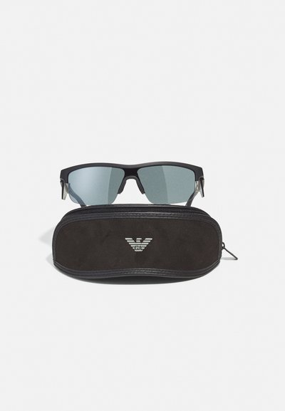 Ochelari negri de soare cu lentile de culoare albastră, design unghiular și accente argintii, însoțiți de o husă moale neagră cu un logo.