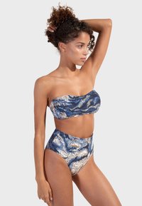 Bikini set pozostávajúci z topu bez ramienok a vysokých plaviek. Materiál s modrými, zlatými a bielymi vlnkovými vzormi; hladká textúra.