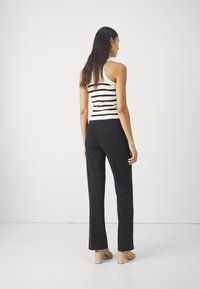 Ermeløs svart og hvit stripet topp parret med høyveide sorte bukser, med rett ben-design og minimalistisk stil.