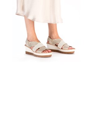 Beige wedge sandalen met een kruisbandontwerp, geperforeerde bovenkant en een gestikte zool. Textuur materiaal en open tenen stijl.