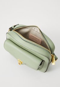 Borsa a tracolla verde in pelle con superficie texturizzata, dettagli in oro, chiusura a zip e una patta con gancio. Interno foderato in tessuto beige.