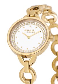 Guldtonet armbåndsur med rund urkasse, hvid urskive, krystal detaljer og en linked kædearmbånd. Markeringerne inkluderer "BREIL TRIBE."