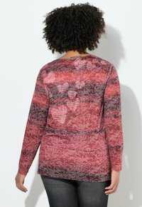 Czerwony top z długim rękawem o fakturowanym wzorze w odcieniach różu i szarości. Wzór zawiera subtelny nadruk i zaokrąglony dół.