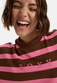 Bruine en roze gestreepte sweatshirt met een hoge hals en Roxy-logo. De stof ziet er zacht en textuurvol uit, met gedurfde horizontale strepen.