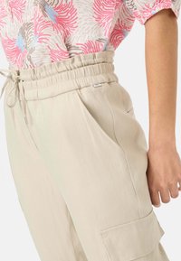 Beige, leichte Cargo-Hosen mit elastischem Bund und Kordelzug. Verfügt über Seitentaschen und einen leicht lockeren Schnitt.
