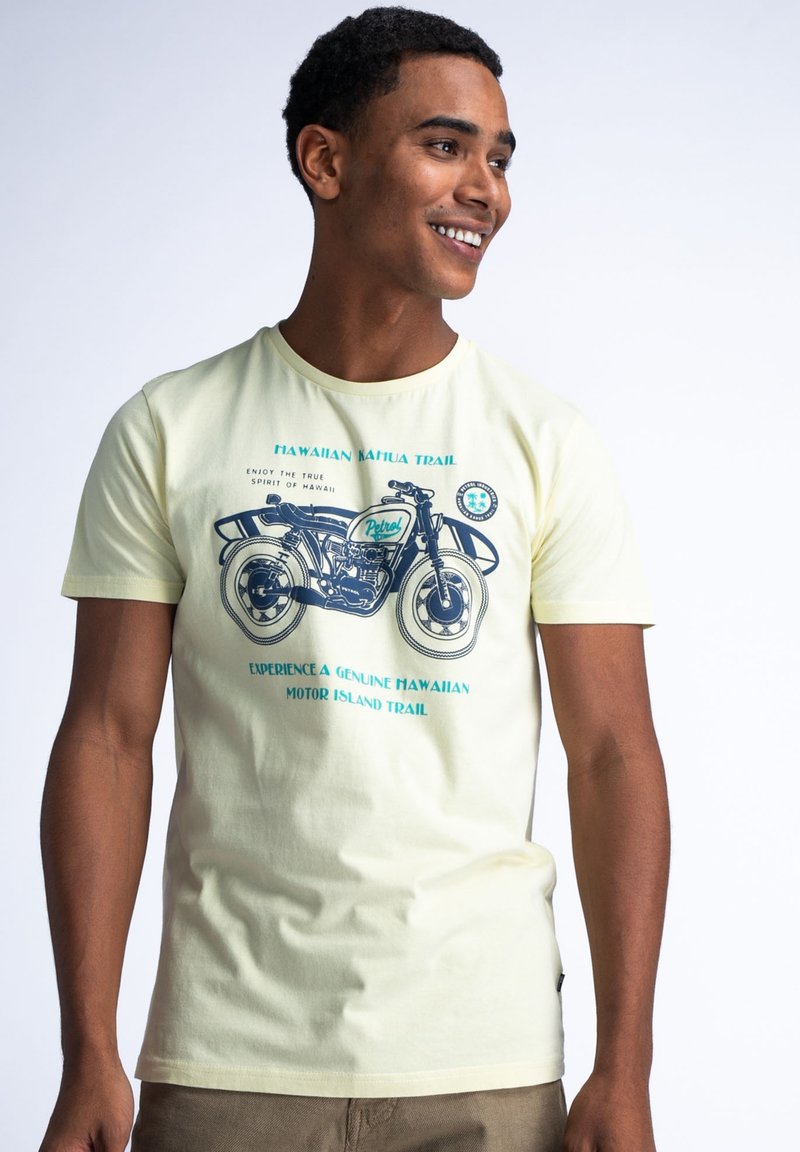 Světle žluté tričko s krátkým rukávem s grafikou motocyklu a modrým textem. Měkký bavlněný materiál, kulatý výstřih, volný střih.