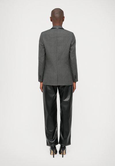 Blazer gris a cuadros con un corte ajustado, combinado con pantalones de imitación de cuero negro de alto brillo. Presenta solapas de muesca y puños abotonados.