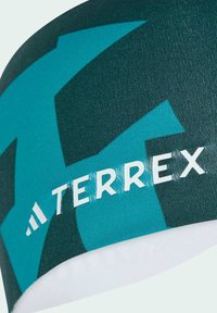 Fascia turchese e verde scuro con la parola "TERREX" in bianco, realizzata in un materiale morbido e elastico con un motivo prominente.
