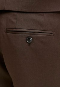 Braune Stoffhosen mit einer hinteren Tasche, die sich horizontal öffnen lässt, und einem schwarzen Knopfverschluss. Glatte Textur mit feinem Gewebe.