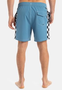 Herren-Badehorts in Blau mit seitlichen Paneelen in Schwarz und Weiß im Schachbrettmuster, elastischem Bund und einer Gesäßtasche mit Klappe. Glattes, leichtes Material.