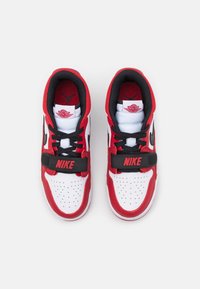 Para czerwono-biało-czarnych butów Nike Air Jordan z czarnymi sznurówkami i czarnym paskiem na górze na białym tle.
