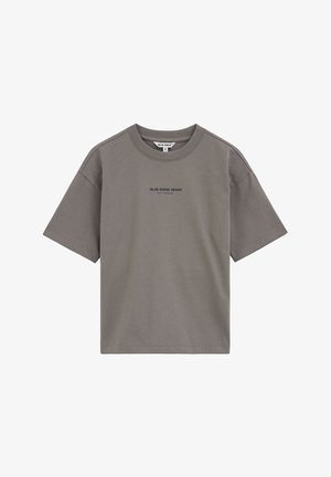 Siva majica kratkih rukava s okruglim izrezom, na prsima su ispisane male riječi "BLUE RIDGE DENIM" u sredini.