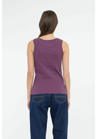Top senza maniche viola con scollatura rotonda e dettagli di cucitura visibili, abbinato a jeans a vita alta blu scuro con tasche posteriori.