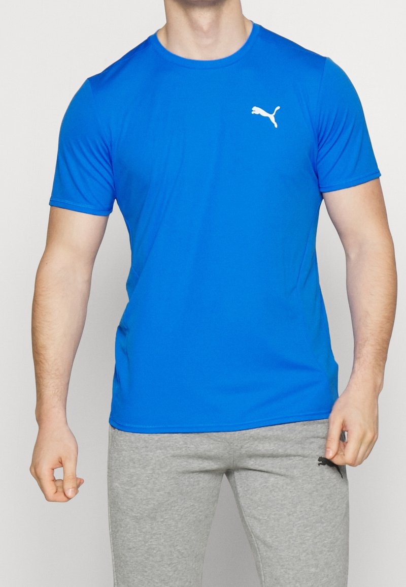 Modré sportovní tričko s krátkým rukávem vyrobené z hladké, lehké tkaniny. Obsahuje bílé logo Puma na levé části hrudi.