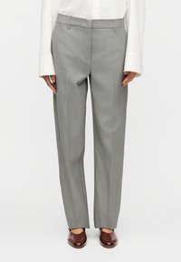 Γκρι παντελόνια με απαλή υφή, σχεδιασμό με ίσια μπατζάκια και επίπεδη μέση, συνδυασμένα με καφέ γυαλιστερά παπούτσια.