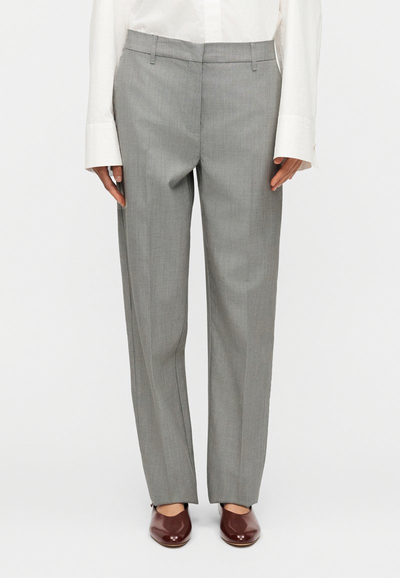 Γκρι παντελόνια με απαλή υφή, σχεδιασμό με ίσια μπατζάκια και επίπεδη μέση, συνδυασμένα με καφέ γυαλιστερά παπούτσια.