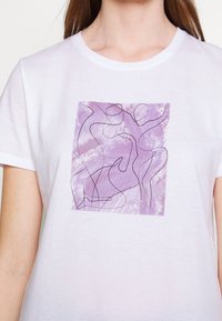 Bílá bavlněná tričko s obdélníkovým fialovým motivem s abstraktními liniemi postav na texturovaném pozadí.