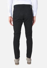 Pantaloni neri in cotone dal design slim fit, con tasche posteriori e un'etichetta discreta in vita. Tessuto liscio senza motivi.