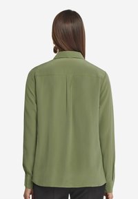 Grüne Polyesterbluse mit langen Ärmeln, einem Rückenfalten und einem Kragen. Glatte Textur, gerade Schnittform und mit Knopfmanschetten.