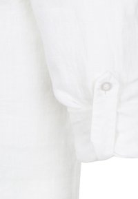 Witte linnen shirtmouw met een knoopdetail, van een gestructureerde stof en een opgerolde manchette. Strak en minimalistisch uiterlijk.