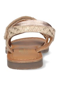 Platte sandalen met een metalen gouden gevlochten band en een gladde bruine leren voetbed. De zool is licht en lichtjes gestructureerd.