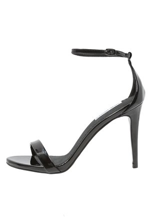 Czarne lakierowane sandały na wysokim obcasie z paskiem na kostkę. Posiadają szeroki pas z przodu i gładkie, błyszczące wykończenie. Obcas typu szpilka o wysokości 12 cm.