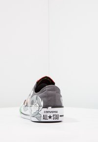 Sneaker in tela grigia con grafiche di cartoni colorati, suola in gomma e branding 'CONVERSE ALL STAR' sul tallone.