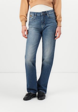 Blauwe spijkerbroek met een straight leg ontwerp, met een lichte wassing, vijf-pocket stijl en een middelhoge taille. Gecombineerd met zwarte schoenen.