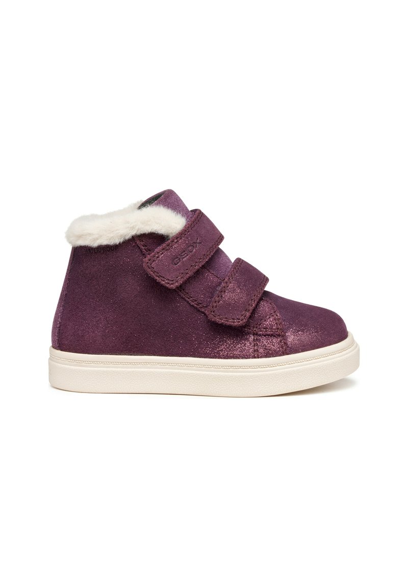 Zapatilla alta infantil morada con forro de piel sintética blanca, dos tiras de velcro y una suela de goma blanca sobre un fondo blanco.