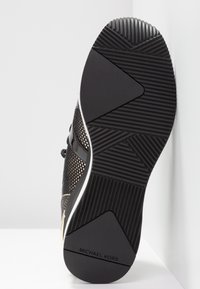 Czarne sneakersy z siateczkową cholewą, gumową podeszwą z teksturowanymi wzorami grip i metalicznym akcentem. "MICHAEL KORS" wytłoczone na podeszwie.