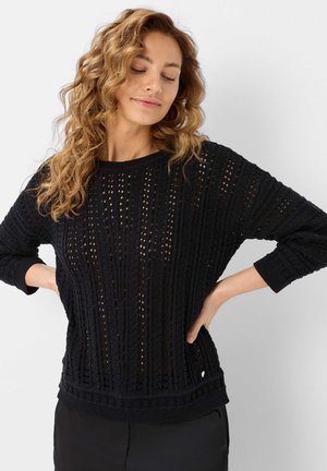 Maglione nero a maglia con vestibilità ampia, motivo a trama aperta e polsini e orlo a costine. Schiena leggermente più lunga con piccolo dettaglio del logo.