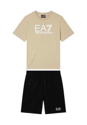 Maglietta beige a maniche corte con logo bianco "EA7 Emporio Armani" abbinata a pantaloncini neri con piccolo logo bianco EA7.