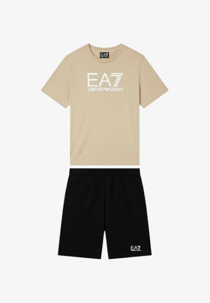 Maglietta beige a maniche corte con logo bianco "EA7 Emporio Armani" abbinata a pantaloncini neri con piccolo logo bianco EA7.