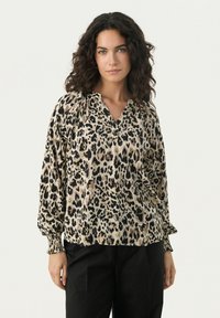 Blouse à imprimé léopard en tissu léger, semblable à du satin. Dotée d'un décolleté en V, de manches froncées et de poignets élastiques. Couleurs noir et beige.