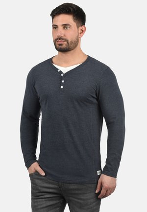 Dark blue long-sleeve henley shirt made of soft fabric, featuring a V-neck, three white buttons, and a small label at the hem.