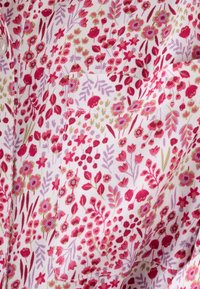 Tela con estampado floral que presenta pequeñas flores rosas y rojas con acentos verdes sobre un fondo blanco. Textura suave y ligera.