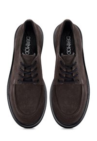 Brown suede shoes with black laces, rounded toe, and a thick black rubber sole. Features a subtle texture and stitched detailing on the upper.