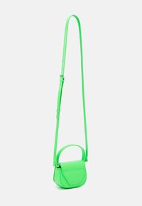 Sac bandoulière vert en matériau lisse, de forme arrondie, avec une courte poignée, une sangle ajustable et un détail de rabat en forme de triangle.