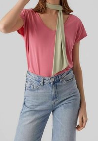 Pink V-neck T-shirt made of soft fabric, paired with high-waisted light blue denim jeans and an olive green neck scarf.