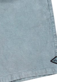 Light blue corduroy shorts featuring a ribbed texture, a straight cut, and a black logo patch on the hem.