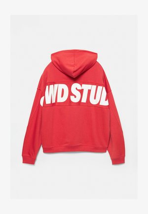 Piros kapucnis pulóver, amelynek hátoldalán egy nagy, fehér grafikával készült felirat található: "WD STUD." Puha anyagból készült, laza szabású és állítható kapucnival rendelkezik.
