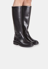 Knöchelhöhe schwarze Lederstiefel mit glatter Oberfläche, runder Zehenpartie, niedrigem Blockabsatz und seitlichem Reißverschluss für einfaches Anziehen.