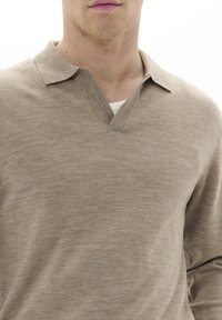 Beige gebreide pullover met een diepe V-hals en korte kraag, voorzien van een zachte textuur en subtiele horizontale strepen.