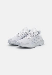 Scarpe sportive bianche con tomaia in rete testurizzata, tre strisce orizzontali, linguetta imbottita e suola in gomma. Design leggero per prestazioni elevate.