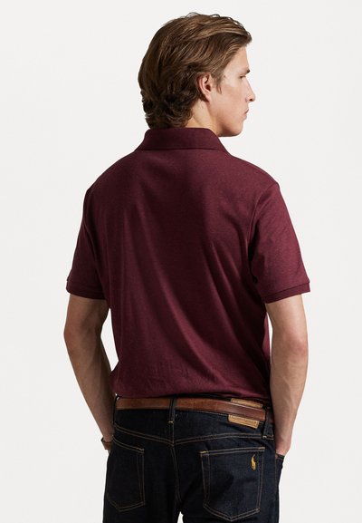 Cămașă polo burgundy cu guler și mâneci scurte, fabricată dintr-un material moale. Purtați-o cu blugi negri și o curea din piele maro.