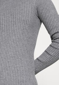Grau gerippter Pullover mit taillierter Silhouette, strukturierter Stoff mit vertikalen Streifen und langen Ärmeln mit subtilen Details.