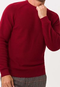 Czerwony sweter z dzianiny z okrągłym dekoltem, ściągaczami przy mankietach i u dołu, o fakturowanej powierzchni oraz raglanowymi rękawami.