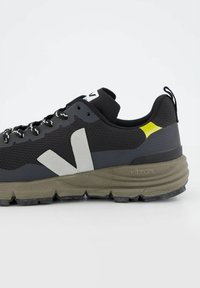 Scarpe da trekking nere con materiali in rete e gomma, dettagli grigi, logo bianco prominente e suola testurizzata con marchio Vibram.