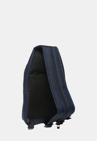 Zaino a tracolla blu navy con pannello posteriore imbottito in mesh, tracolla regolabile e due scomparti verticali con cerniera.